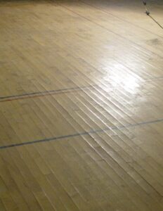 Failed gymnasium floor due to moisture.