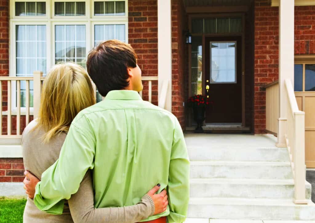 Young Happy Couple in Front of House