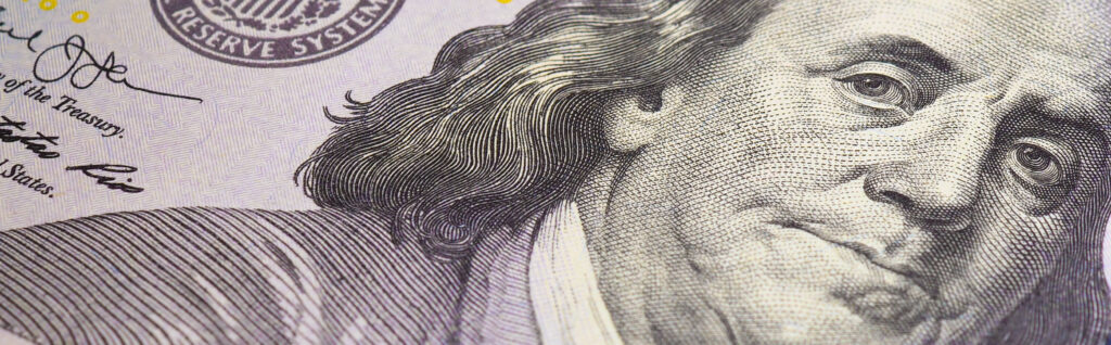 American paper money. A $100 bill with focus on eyes of Benjamin Franklin. US banknotes close-up. Savings economy and the USA dollar. Banner or headline. Macro