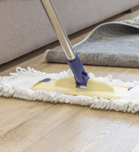 Cleaning floor with mop under carpet in living room, concept of good cleaning service